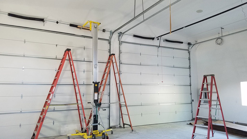 inside unfinished garage with three orange ladders standing in middle of room
